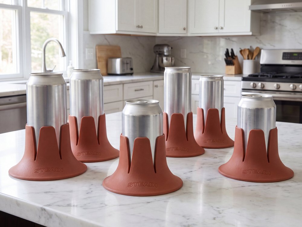 Six terracotta Steadis in a row, each holding a different size of aluminium can, on a kitchen counter.